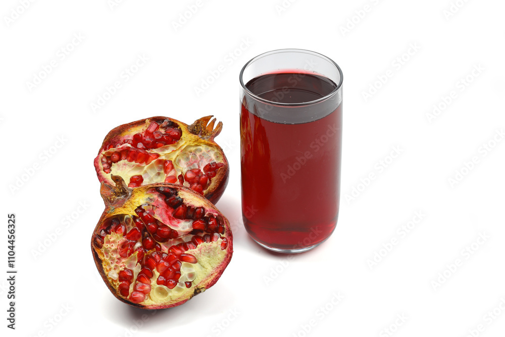 Freshly squeezed pomegranate juice in a glass transparent bottle, broken pomegranate and pomegranate seeds on a black flat stone plate on a dark wooden background top view. Freshly squeezed pomegranate juice in a glass transparent bottle, broken pomegranate and pomegranate seeds on a black flat stone plate on a dark wooden background top view.