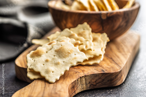 A crispy salted crackers on cutting board on black table.