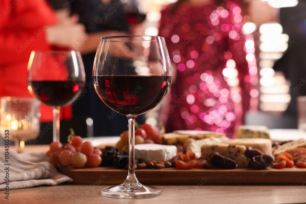 People holding glasses of wine at party, focus on wooden table with snacks and alcohol People holding glasses of wine at party, focus on wooden table with snacks and alcohol