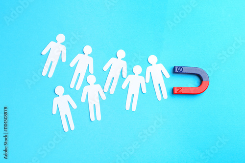 Valokuva Magnet attracting paper cutouts of humans on light blue background, flat lay