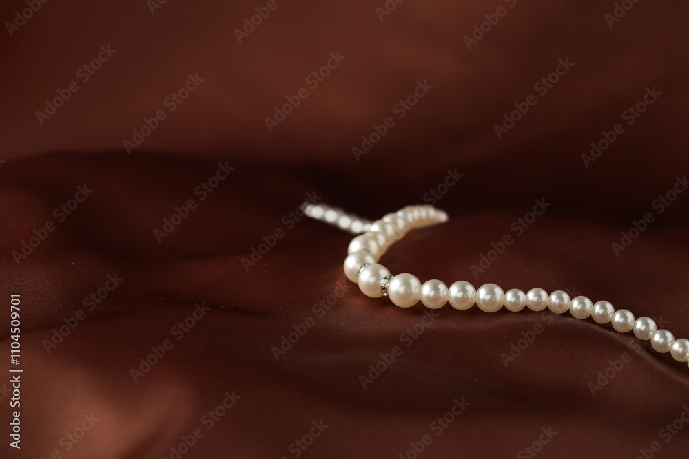 Beautiful pearl necklace on brown silk, closeup. Space for text Beautiful pearl necklace on brown silk, closeup. Space for text
