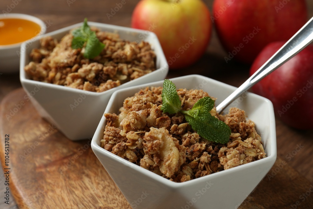 Tasty apple crisp in bowls, fresh fruits and spoon on table, closeup Tasty apple crisp in bowls, fresh fruits and spoon on table, closeup