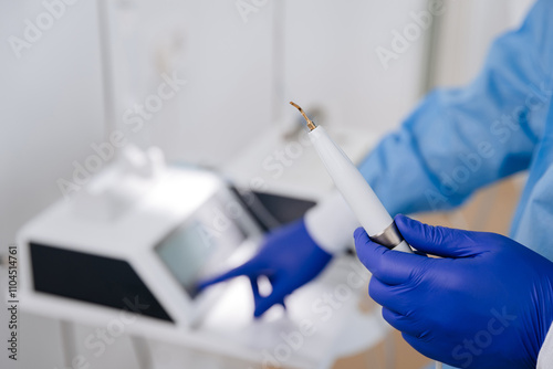 Dental professional preparing ultrasonic scaler for teeth cleaning in a modern dental clinic