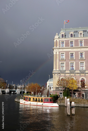 Obraz na płótnie Amstel Hotel on the Amstel River in Amsterdam, the Netherlands, with saloon boat and rainbow w salonie