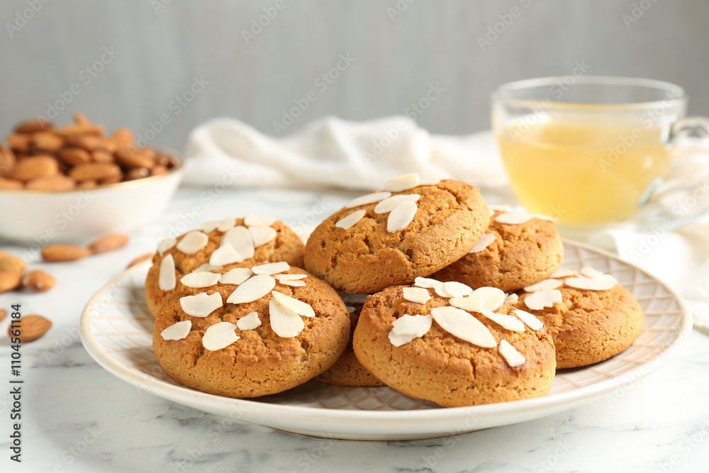Tasty cookies with almond flakes, nuts and tea on white marble table, closeup Tasty cookies with almond flakes, nuts and tea on white marble table, closeup