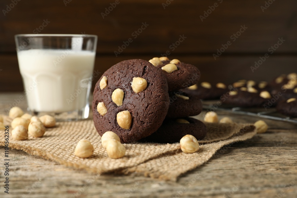 Tasty chocolate cookies with hazelnuts and milk on wooden table, closeup Tasty chocolate cookies with hazelnuts and milk on wooden table, closeup
