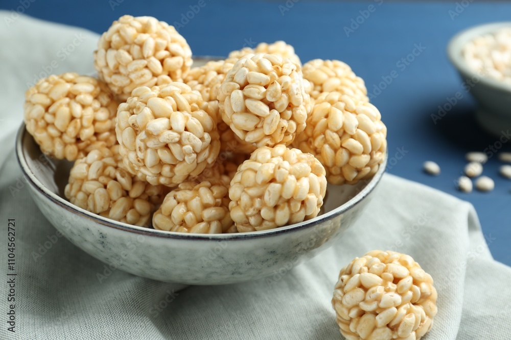 Tasty puffed rice balls in bowl on blue table, closeup Tasty puffed rice balls in bowl on blue table, closeup
