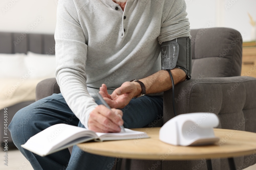 Senior man writing results of blood pressure measurement at home, closeup Senior man writing results of blood pressure measurement at home, closeup