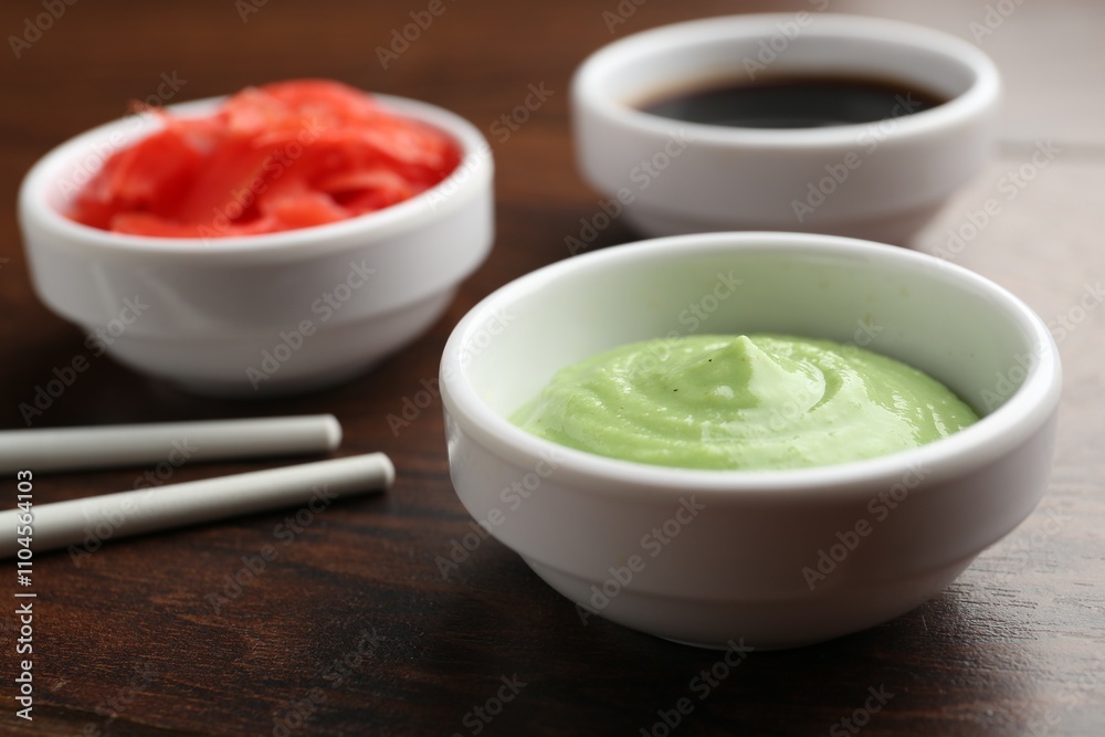 Hot wasabi paste, soy sauce, ginger and chopsticks on wooden table, closeup Hot wasabi paste, soy sauce, ginger and chopsticks on wooden table, closeup