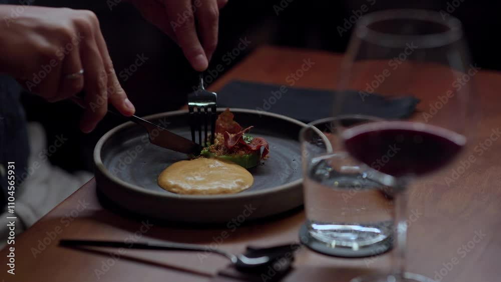 Close-up view of a good looking man eating roasted carrot with royal oyster mushroom. He is eating with fork and knife Close-up view of a good looking man eating roasted carrot with royal oyster mushroom. He is eating with fork and knife