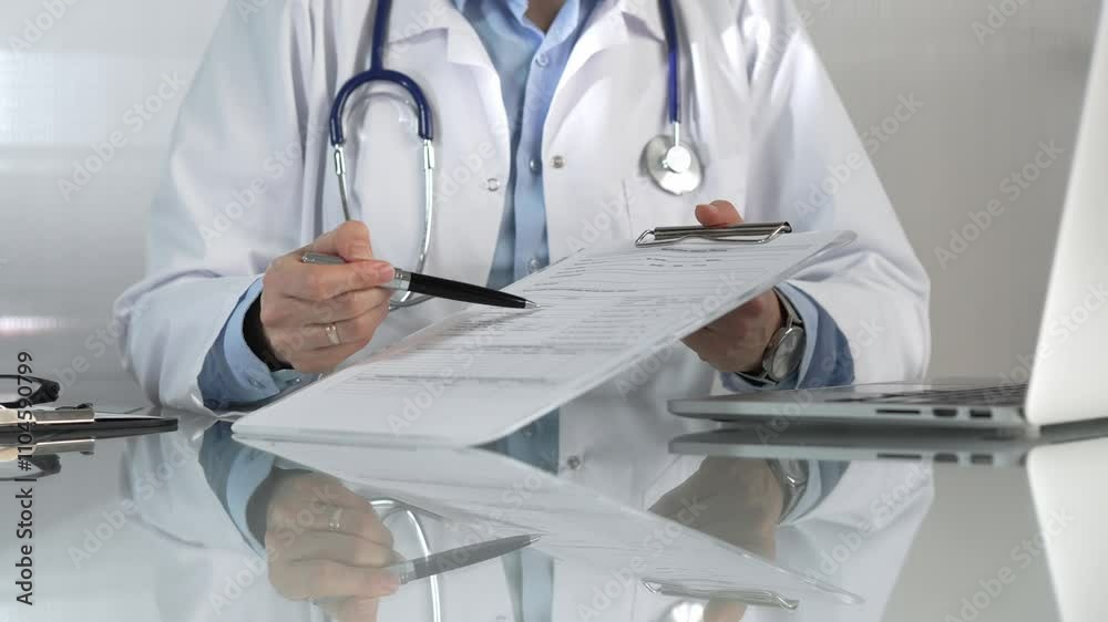Female doctor, wearing a blue blouse under a medical coat, is pointing at medical chart, showcasing expertise in a close up shot. Medicine concept Female doctor, wearing a blue blouse under a medical coat, is pointing at medical chart, showcasing expertise in a close up shot. Medicine concept