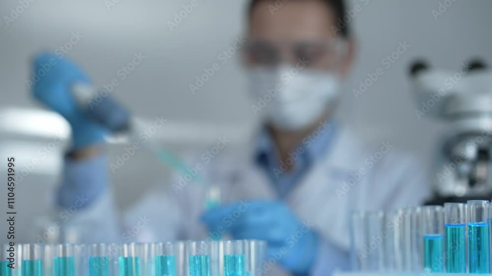 Laboratory tubes are in focus, closeup view. Female scientist researcher is using a micropipette at the background. Medicine and science concept Laboratory tubes are in focus, closeup view. Female scientist researcher is using a micropipette at the background. Medicine and science concept