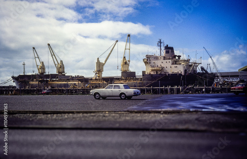 A vintage photo a ship at the dockside with a car