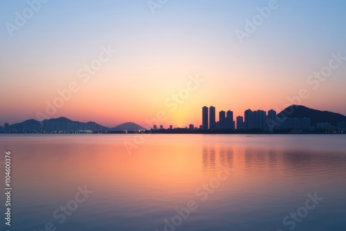 Peaceful urban sunset over calm waterfront and distant city skyline