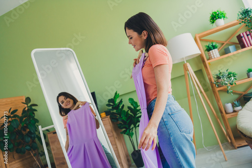 Young woman in striped t-shirt choosing an outfit at home, admiring herself in the mirror while enjoying a casual and stylish weekend photo