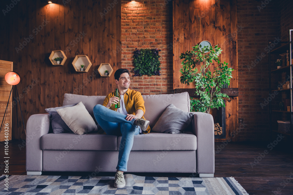 Obraz premium Young man enjoying leisure time indoors on a cozy weekend afternoon in a stylish living room