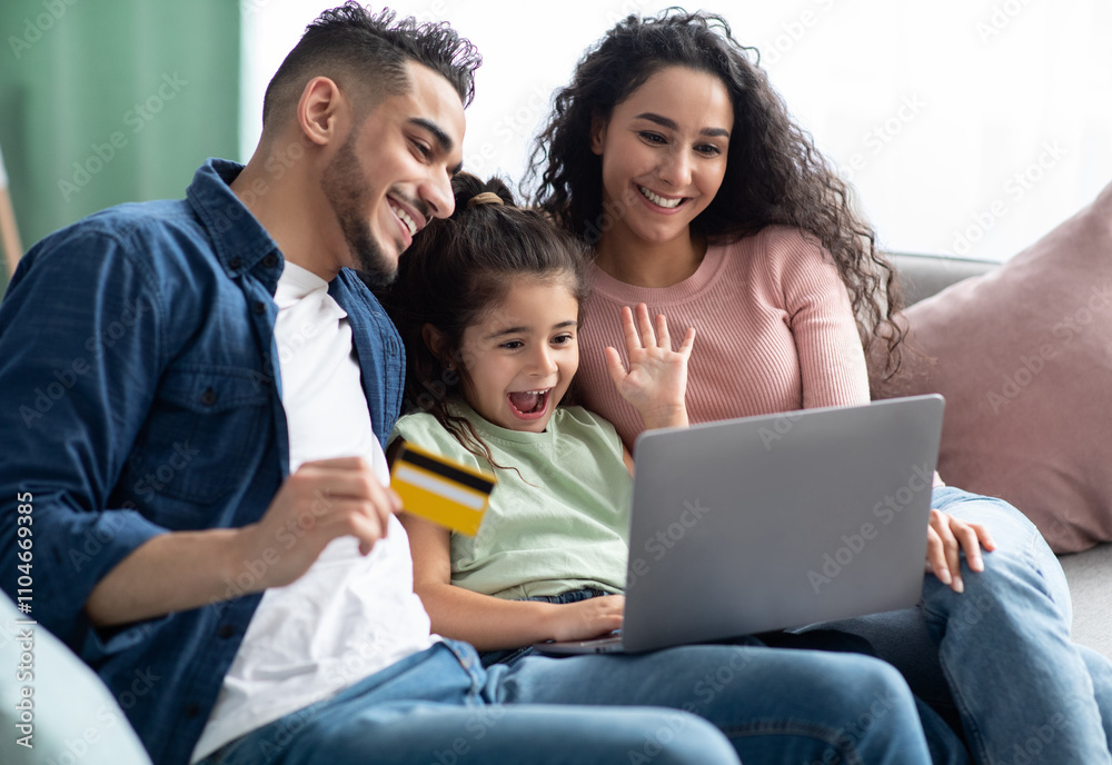 Cheerful Arabic Family Of Three With Laptop And Credit Card Making Online Shopping While Relaxing On Couch At Home, Happy Middle Eastern Parents And Little Daughter Enjoying Purchase From Internet Cheerful Arabic Family Of Three With Laptop And Credit Card Making Online Shopping While Relaxing On Couch At Home, Happy Middle Eastern Parents And Little Daughter Enjoying Purchase From Internet
