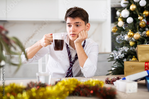 untidy man suffering from headache while hungover after new year party photo