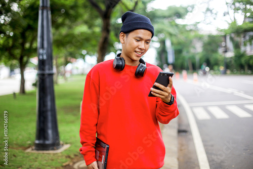 Portrait of Young Asian Man In Casual Style Using Smartphone While Waiting Transports photo