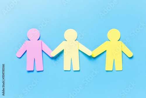 Colorful paper figures holding hands on a blue background, symbolizing unity, friendship, and teamwork. Creative concept of togetherness and collaboration.