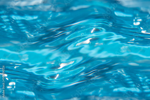 Blue water with ripples on the surface. Defocus blurred transparent blue colored clear calm water surface texture with splashes and bubbles. Water waves with shining pattern texture background.