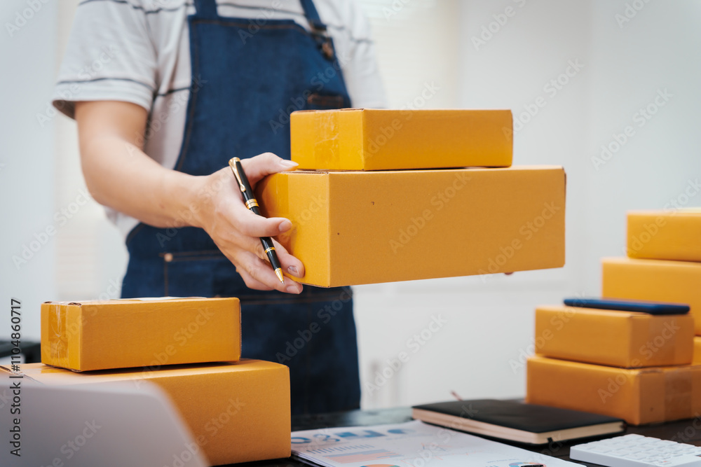 Close-up of a businessman’s hand packing items at a desk, preparing products for shipping. Highlighting delivery services for private companies online shopping with credit cards for convenience Close-up of a businessman’s hand packing items at a desk, preparing products for shipping. Highlighting delivery services for private companies online shopping with credit cards for convenience