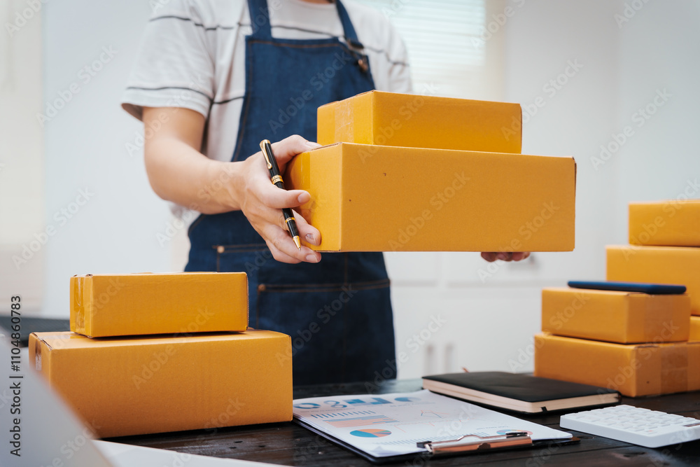 Close-up of a businessman’s hand packing items at a desk, preparing products for shipping. Highlighting delivery services for private companies online shopping with credit cards for convenience Close-up of a businessman’s hand packing items at a desk, preparing products for shipping. Highlighting delivery services for private companies online shopping with credit cards for convenience