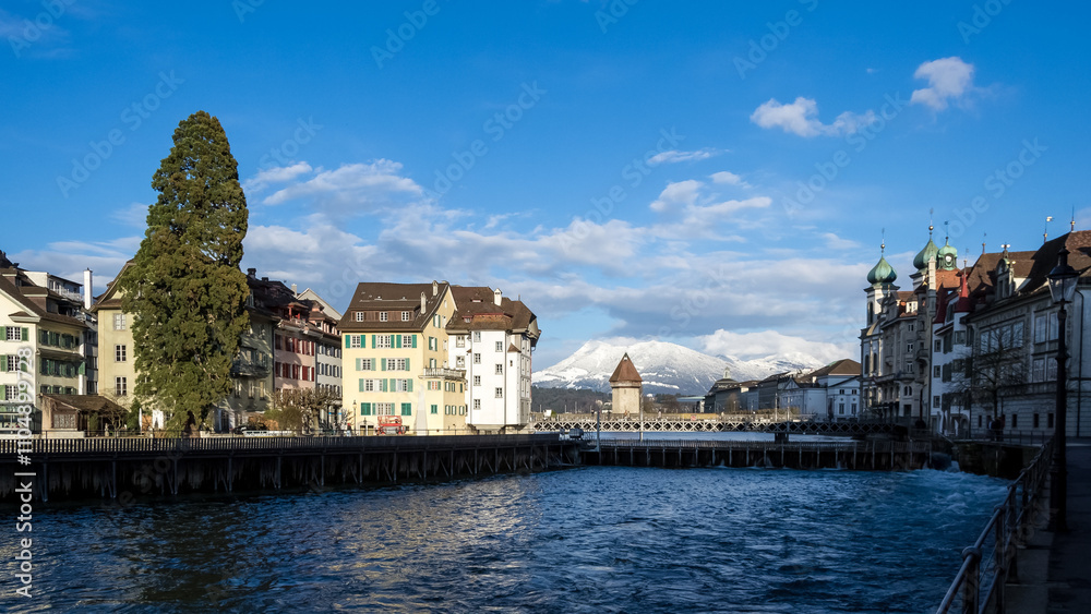 Fototapeta premium View of the Old Town (Altstadt) of Lucerne, Switzerland, with the Kapellbrücke (Chapel Bridge), the oldest wooden covered bridge in Europe, spanning the Reuss River far in the background.