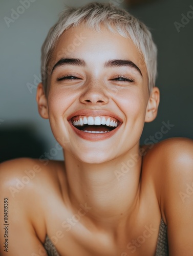 Attractive woman with short fair hair being very glad smiling with broad smile showing her perfect teeth having fun indoors. Joyful excited cheery femlae rejoicing after being proposed to marry photo