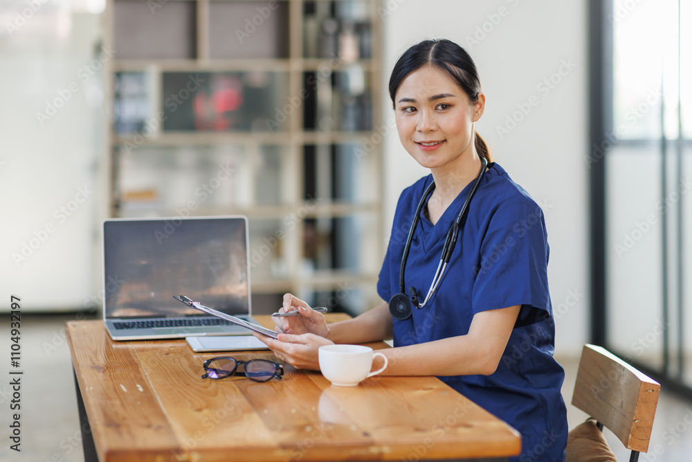 Female Asian female doctor or nurse sitting at laptop computer in clinic Female Asian female doctor or nurse sitting at laptop computer in clinic