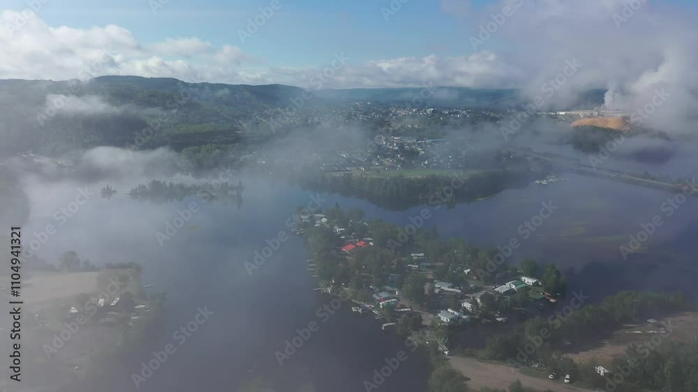 Aerial View of a Foggy Riverside Town Transitioning to a Clear Morning Sky, Featuring Lush Green Hills and Reflections on the Water Aerial View of a Foggy Riverside Town Transitioning to a Clear Morning Sky, Featuring Lush Green Hills and Reflections on the Water