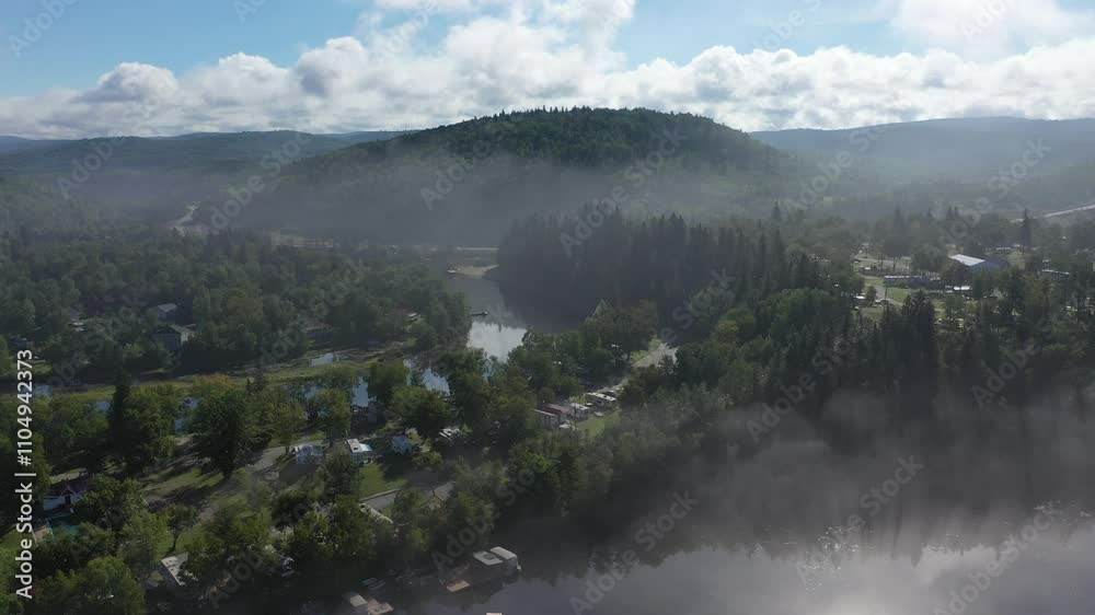 Foggy Mountain View with Lush Greenery and Serene River Under Bright Blue Sky Foggy Mountain View with Lush Greenery and Serene River Under Bright Blue Sky