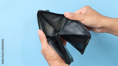 Man shows his empty shabby wallet isolated on blue background. Bankruptcy and financial problems concept