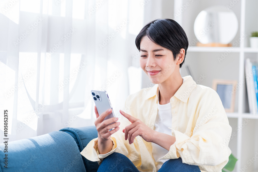 リビングでスマホを操作する若い女性。 リビングでスマホを操作する若い女性。
