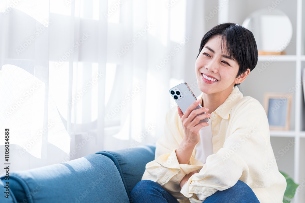 リビングでスマホを操作する若い女性。 リビングでスマホを操作する若い女性。