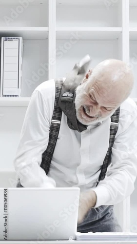 Stressed crazy businessman smashing his laptop in the office using a baseball bat, anger and computer problem concept