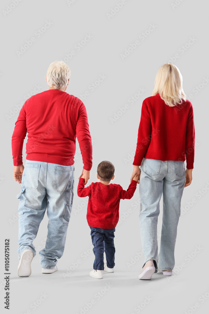 Cute little boy with happy grandparents in warm sweaters on grey background, back view Cute little boy with happy grandparents in warm sweaters on grey background, back view