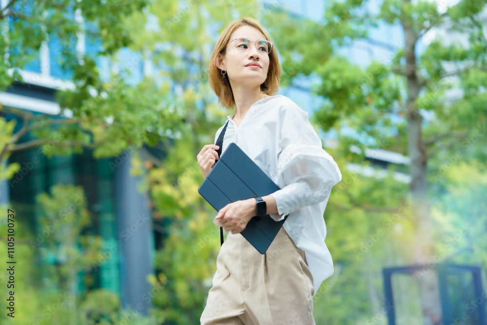 緑あふれるオフィス街を歩く女性