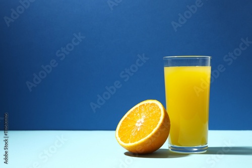 Glass of freshly squeezed orange juice on color background 