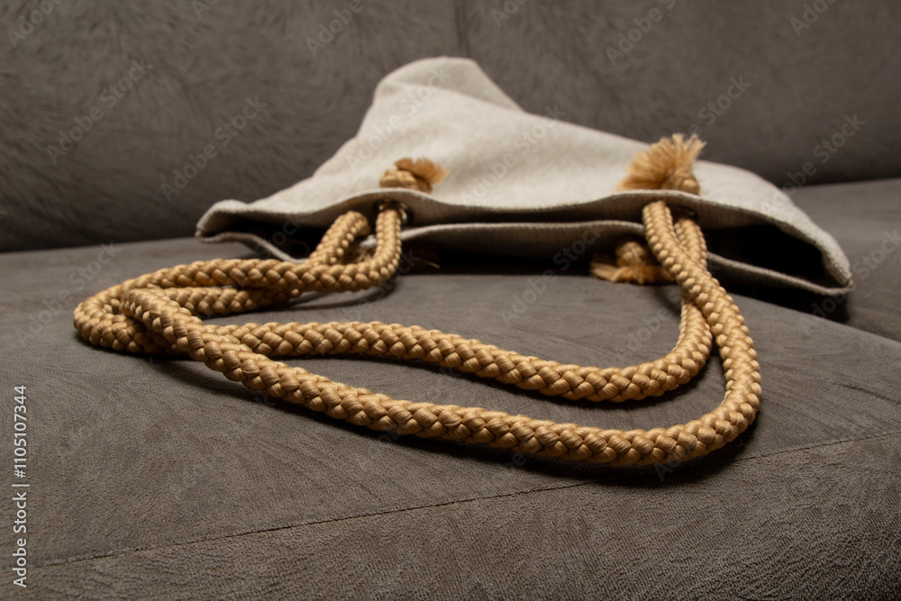 Fototapeta premium the appearance of a tote bag or backpack draped over a gray sofa with a close-up photo with a wick strap