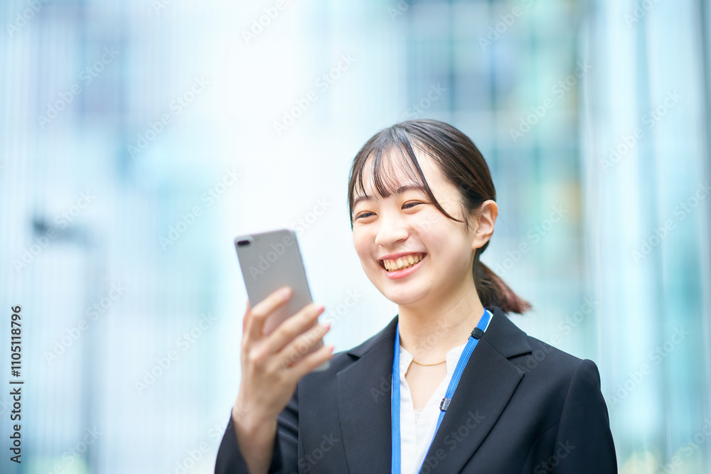 スマートフォンの画面を見るスーツ姿の若い女性 スマートフォンの画面を見るスーツ姿の若い女性