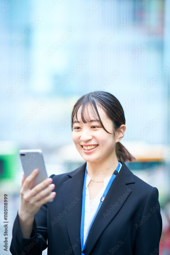 スマートフォンの画面を見るスーツ姿の若い女性 スマートフォンの画面を見るスーツ姿の若い女性
