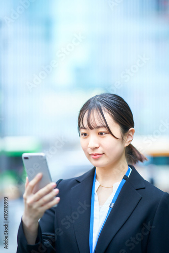 スマートフォンの画面を見るスーツ姿の若い女性