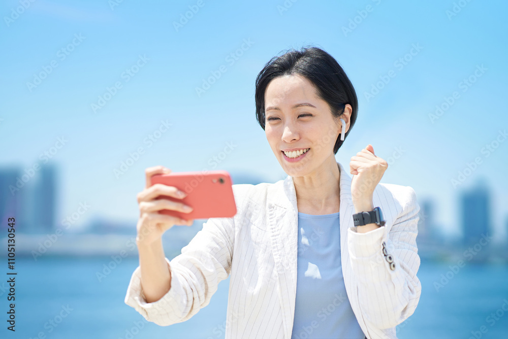 スマートフォンの画面を見ながら応援するビジネスウーマン スマートフォンの画面を見ながら応援するビジネスウーマン