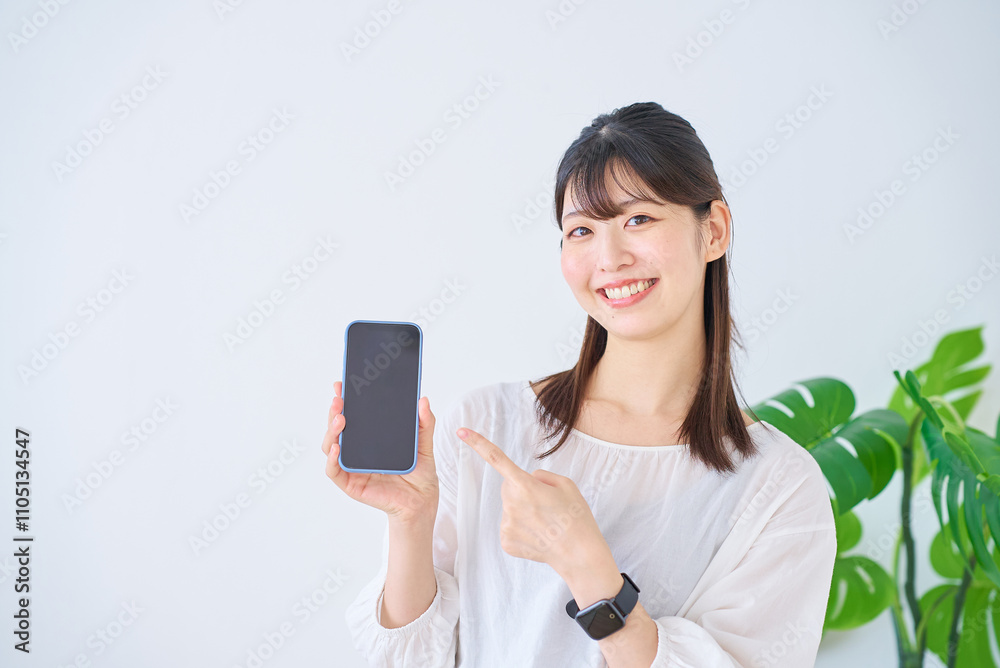 Fototapeta premium スマートフォンを指差す若い女性