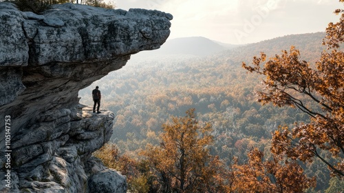 A youn man smiles while looking off a rock overhang at Cheaha Mountain. photo
