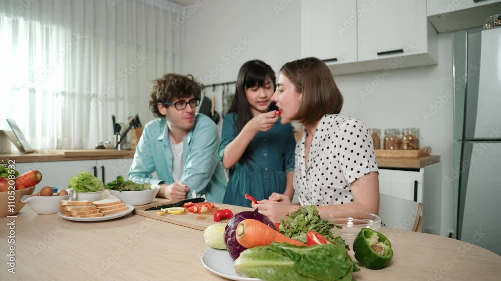 Attractive caucasian father and mother spend time together to cook fresh meal with asian daughter. Dad and mom preparing fresh vegetable for making salad at kitchen and eating vegetable. Pedagogy.
