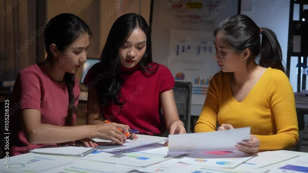 Three women are sitting around a table with papers and pens. They are discussing something and seem to be working on a project. Scene is focused and collaborative Three women are sitting around a table with papers and pens. They are discussing something and seem to be working on a project. Scene is focused and collaborative