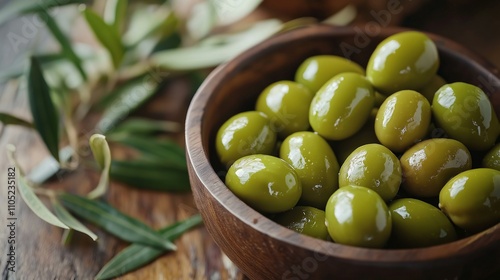 Fresh green olives in a rustic wooden bowl, surrounded by olive leaves on a natural wooden table.