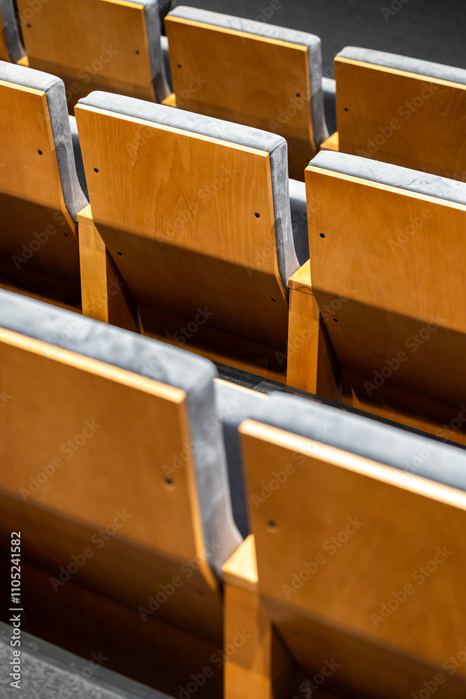 Rows of empty seats in a cinema hall - close-up with shallow depth of field. View of the back part made of light plywood.